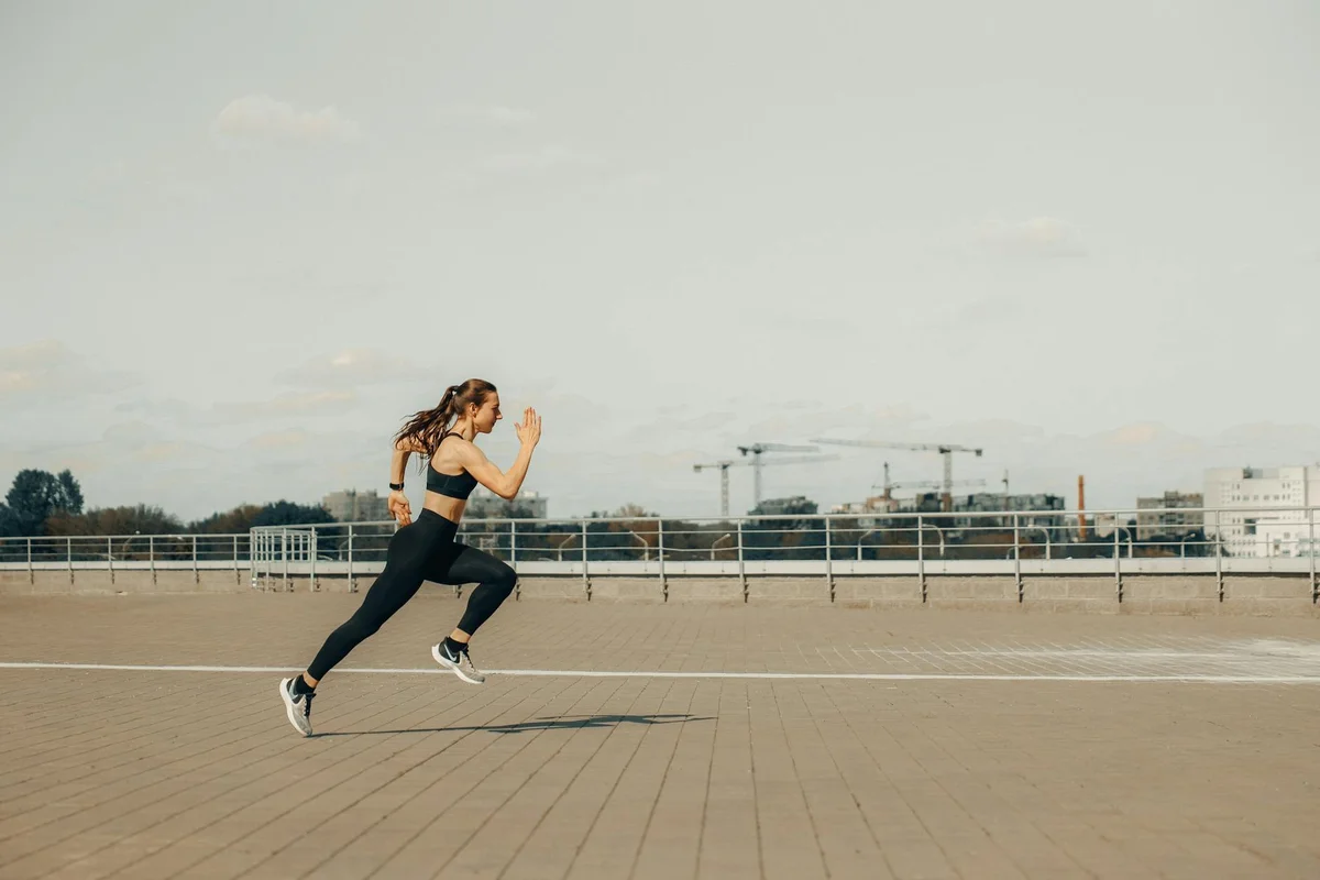 A person in athletic wear runs across a large, open paved area, illustrating motion and elasticity.