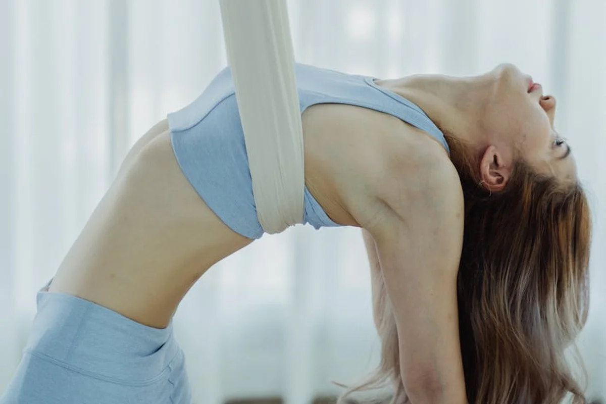 Woman in light blue athletic wear performing a backbend stretch in a bright studio