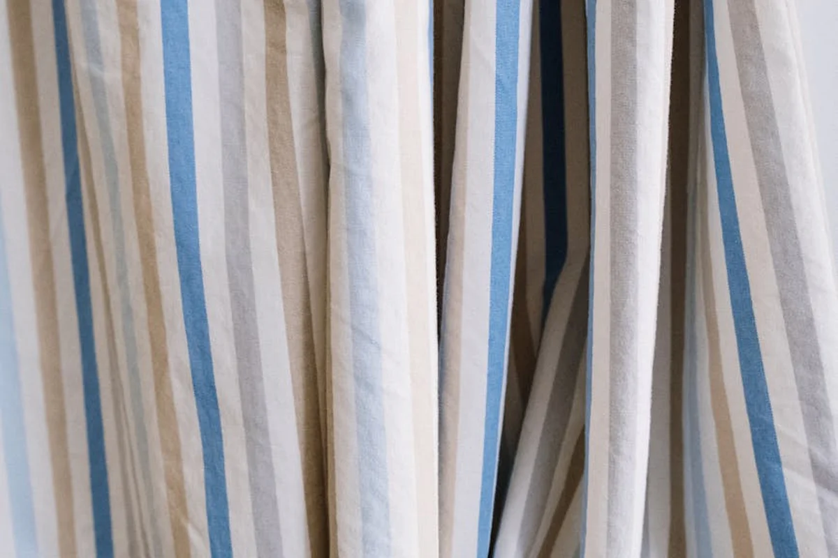 Rows of vertical striped fabrics in beige and blue, hanging on racks.