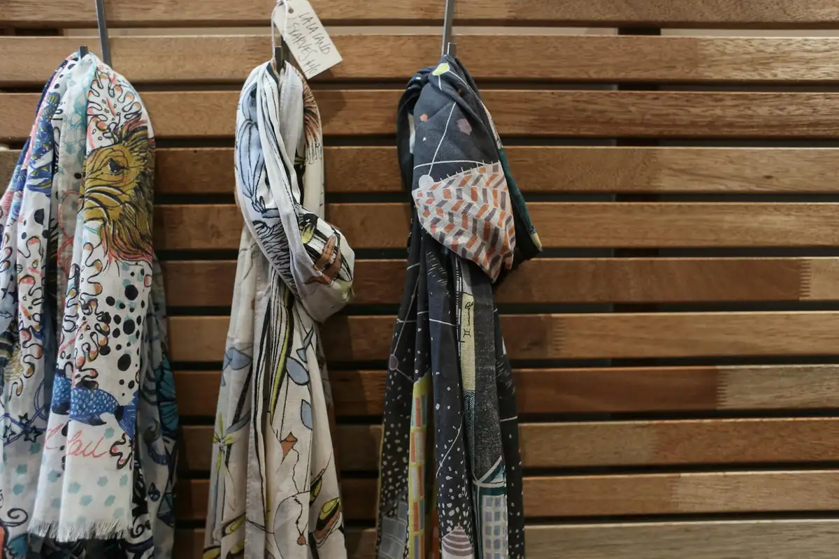 Colorful printed scarves hanging on a wooden wall, representing fabrics that may be sublimation-printed.