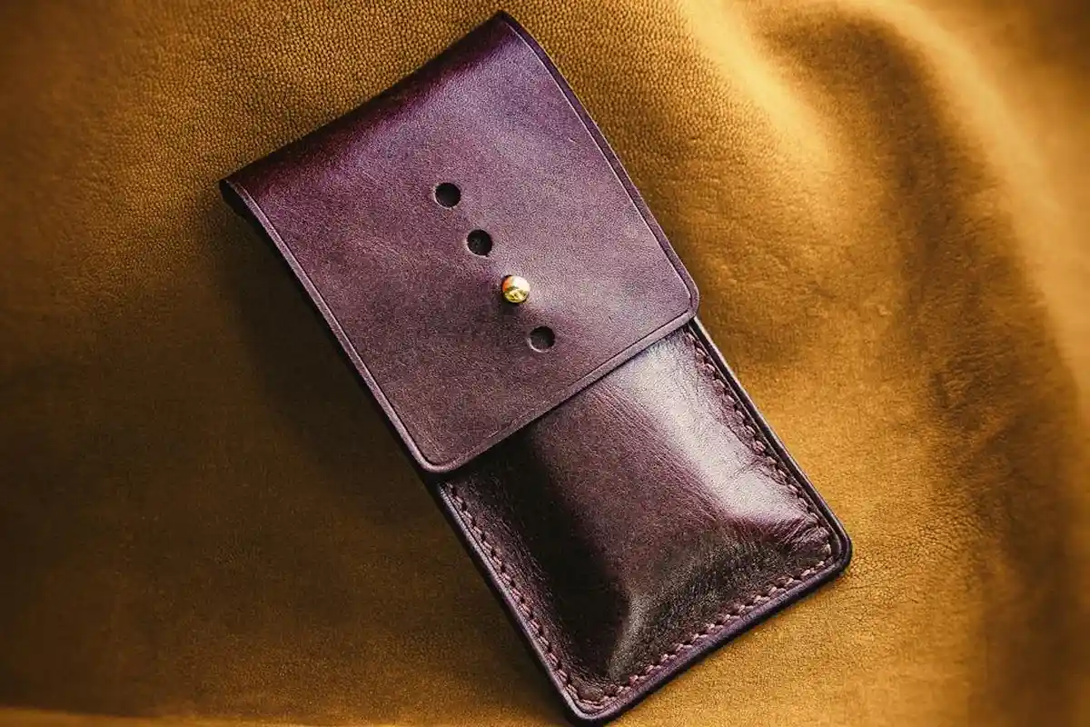 Dark brown leather pouch on a warm mustard suede background, highlighting texture and nap.