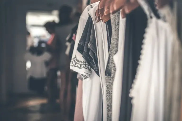 Display of clothing on hangers in a boutique with a blurred background, highlighting fabrics and textures