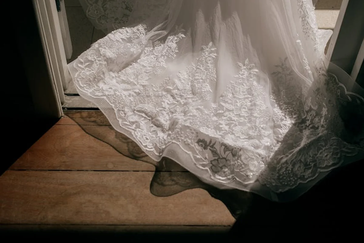 White lace fabric draped over a wooden floor near a doorway, illuminated by natural light.