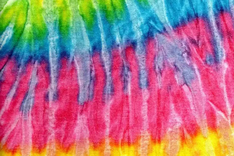 Close-up of vibrant rainbow tie-dyed fabric with green, blue, pink, and yellow tones.