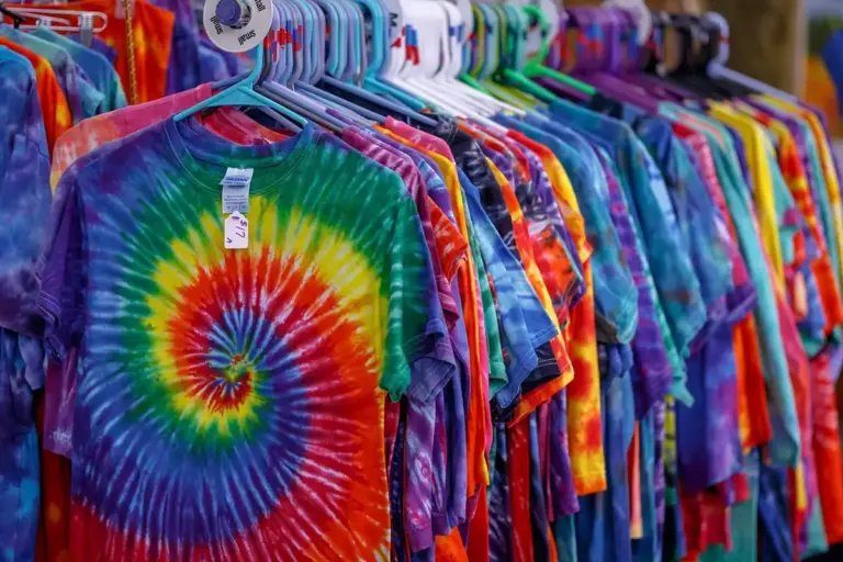 Row of colorful rainbow tie-dye T-shirts on hangers in a store display
