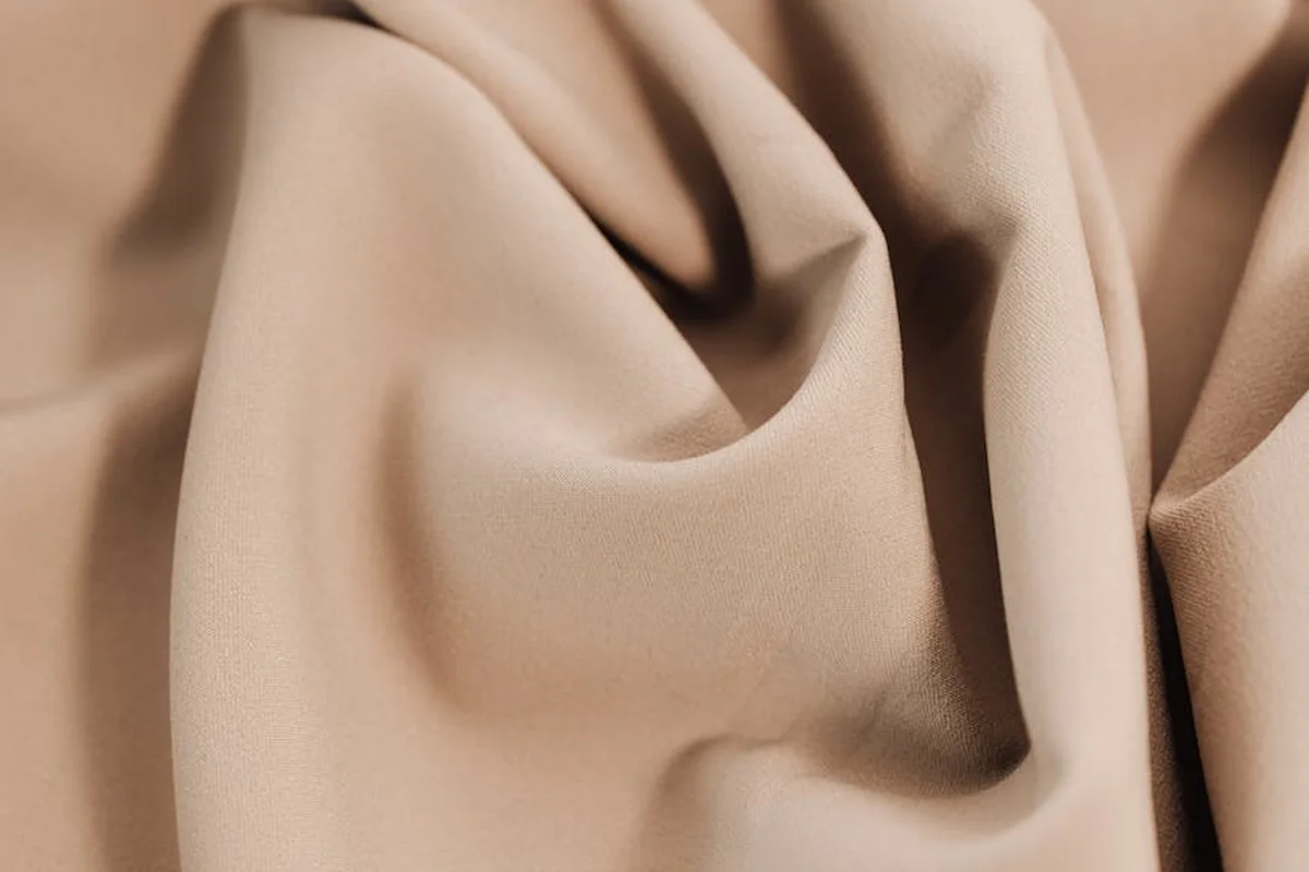 Close-up of beige velvet fabric with soft folds and rich texture.