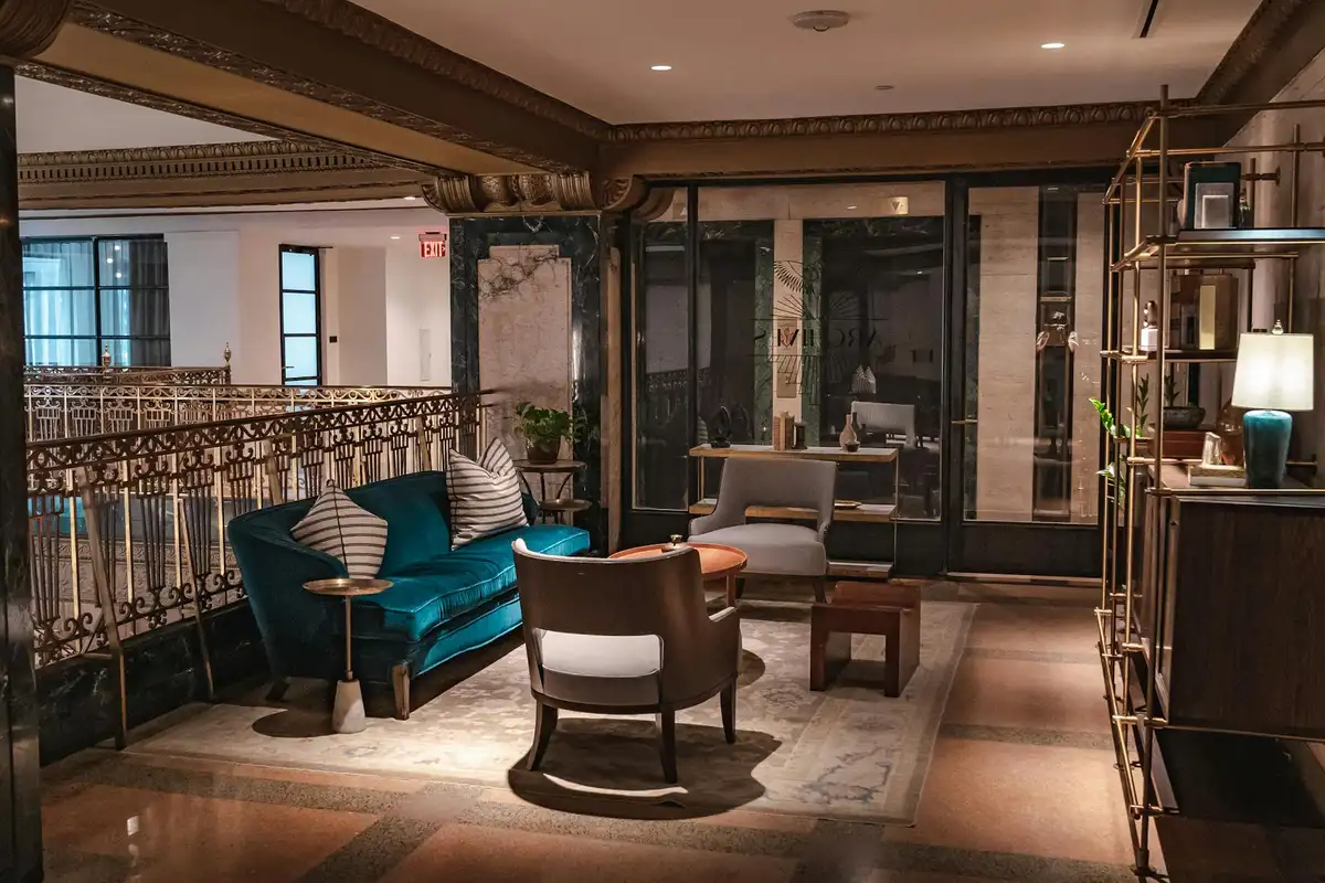 Luxurious hotel lobby featuring teal velvet seating and a brown leather chair with warm lighting