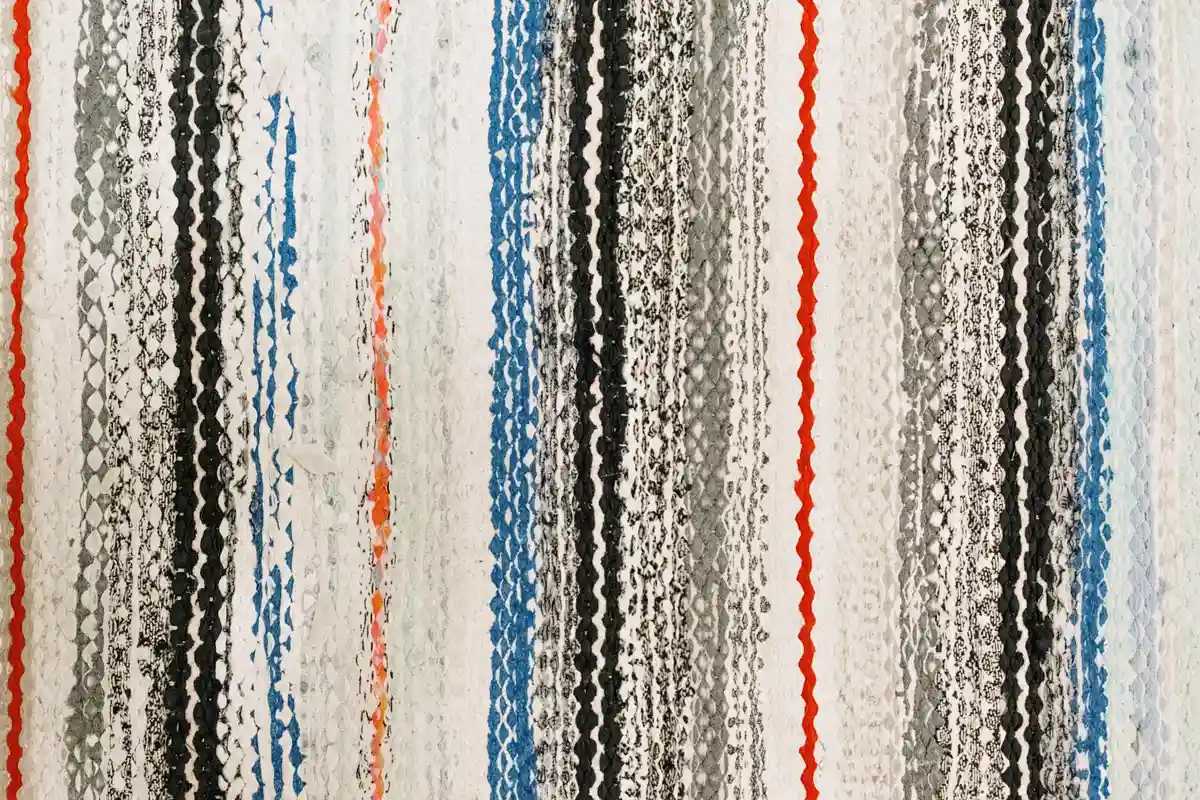 Close-up of vertical striped woven fabric with blue, black, white, gray, and red stripes.