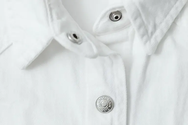 Close-up of a white collared shirt with metal snap buttons