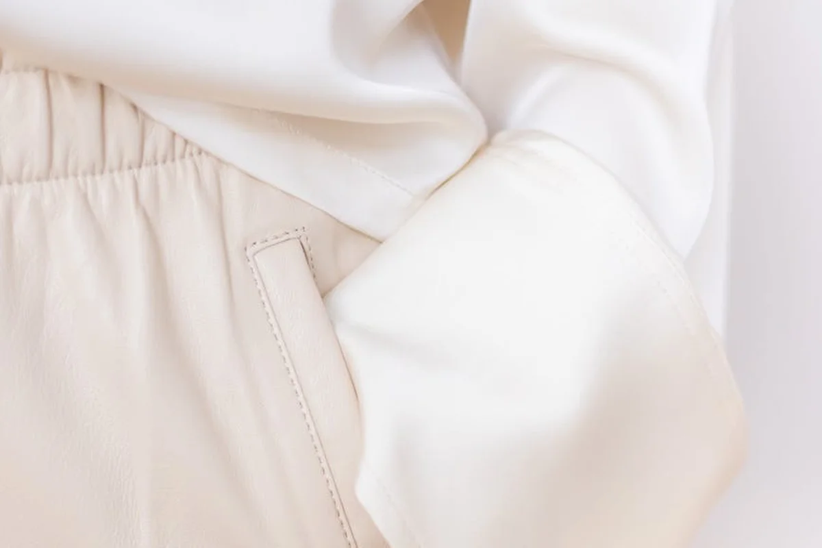 Close-up of light beige viscose fabric with a stitched pocket seam