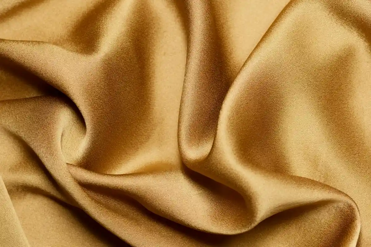 Close-up of soft, beige viscose/rayon fabric with graceful folds and drape.