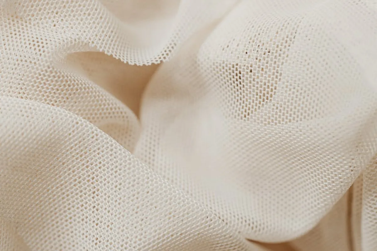 Close-up of cream-colored viscose fabric with a fine, mesh-like weave.