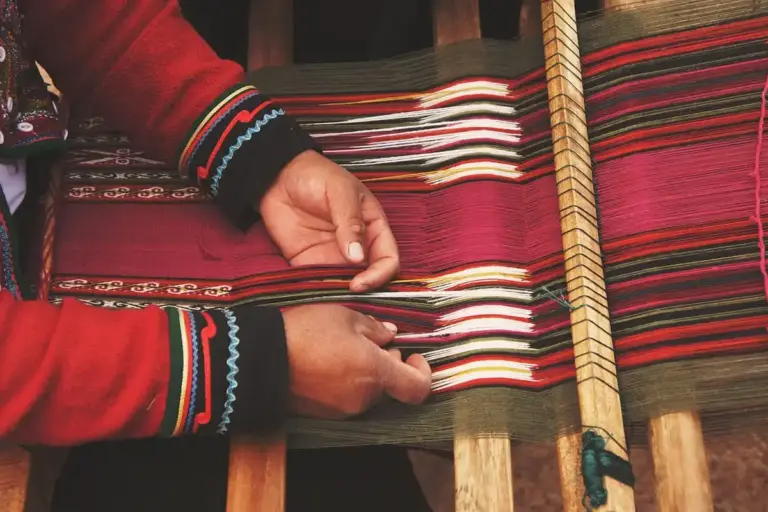 Close-up of hands weaving colorful striped fabric on a wooden loom