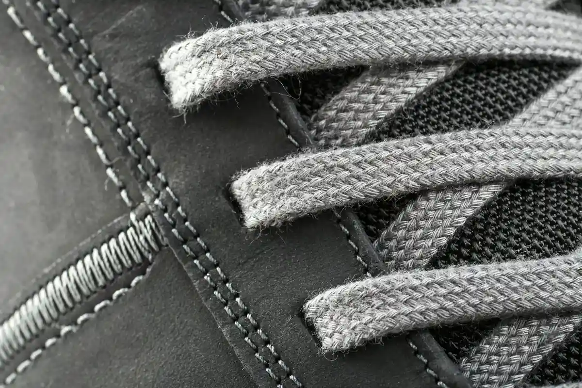 Close-up of gray laces on dark fabric with visible stitching, highlighting the texture differences between moleskin and suede cloth.