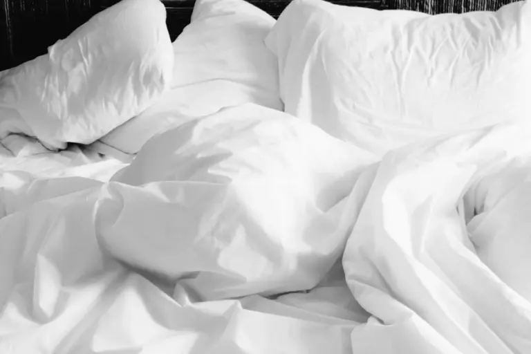 Close-up of white bedsheets and pillows with soft folds on a bed.