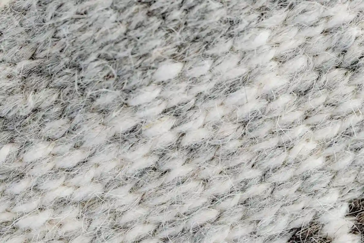 Close-up of a textured gray and white wool fabric showing fuzzy, interwoven fibers