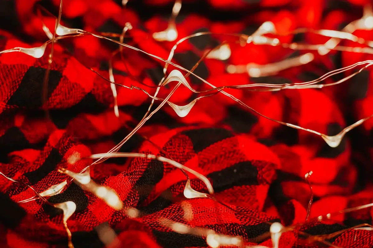 Close-up of red plaid wool flannel fabric with a brushed, textured surface and scattered white fibers
