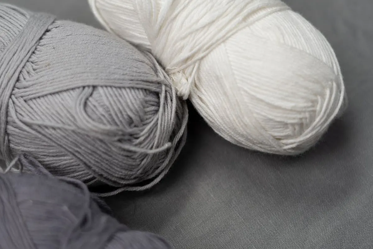 Gray and white wool yarn skeins on a dark fabric background