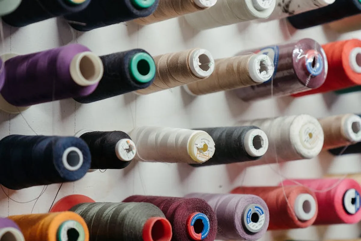 Rows of colorful thread spools mounted on a rack in a textile workshop.
