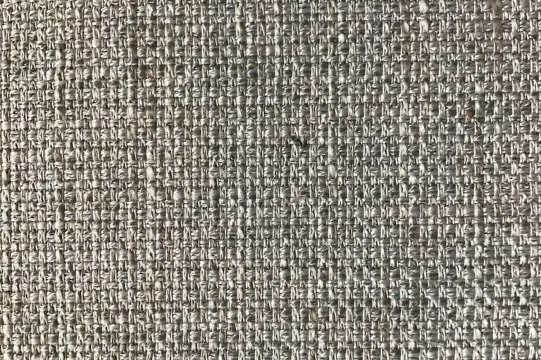 Close-up view of a grey-brown woven fabric showing interlaced threads, typical of base-layer materials.