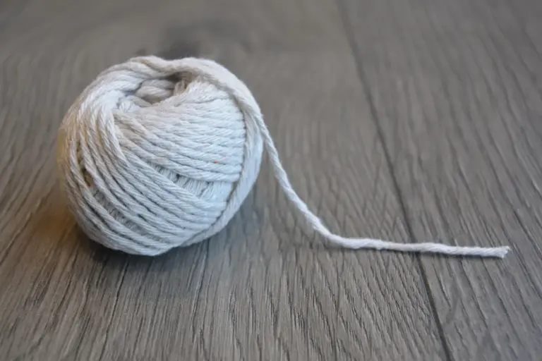 A ball of natural fiber yarn on a wooden floor